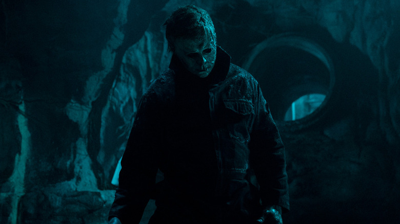 Michael Myers (James Jude Courtney) stands wearing a decayed mask in the sewers in Halloween Ends