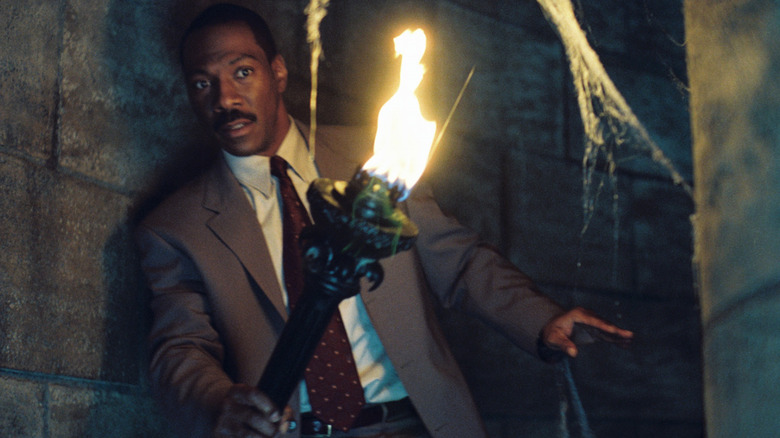 Eddie Murphy as Jim Evers holds a torch in a staircase in The Haunted Mansion (2003)