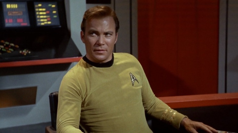 James T. Kirk (William Shatner) looks over while seated in the captain's chair in Star Trek: The Original Series