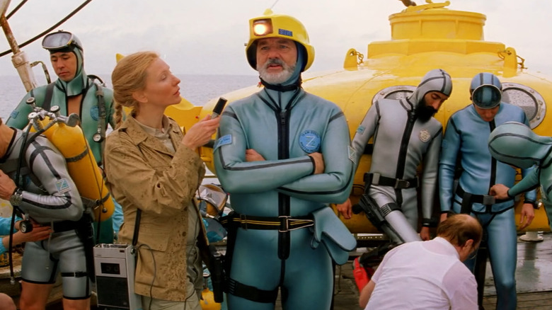 Bill Murray as Steve Zissou, being interviewed surrounded by his crew in front of a submarine in The Life Aquatic with Steve Zissou