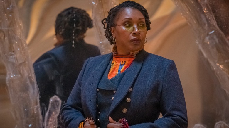 The Fugitive Doctor (Jo Martin) adjusts her jacket near crystalline outcroppings in Doctor Who