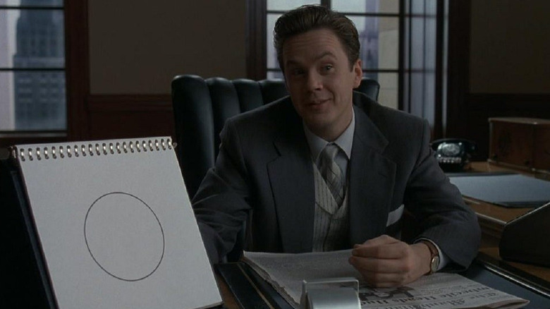Tim Robbins as Norville Barnes holds up a drawing of a circle, ya know, for kids, in The Hudsucker Proxy