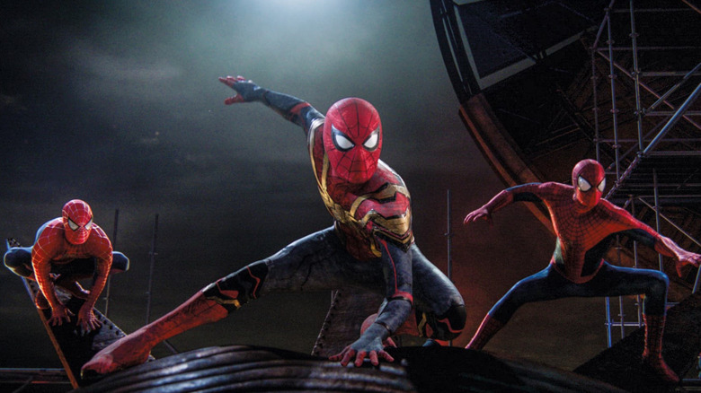 Spider-Men (Tobey Maguire, Tom Holland and Andrew Garfield) crouched and ready to fight on the Statue of Liberty in Spider-Man: No Way Home