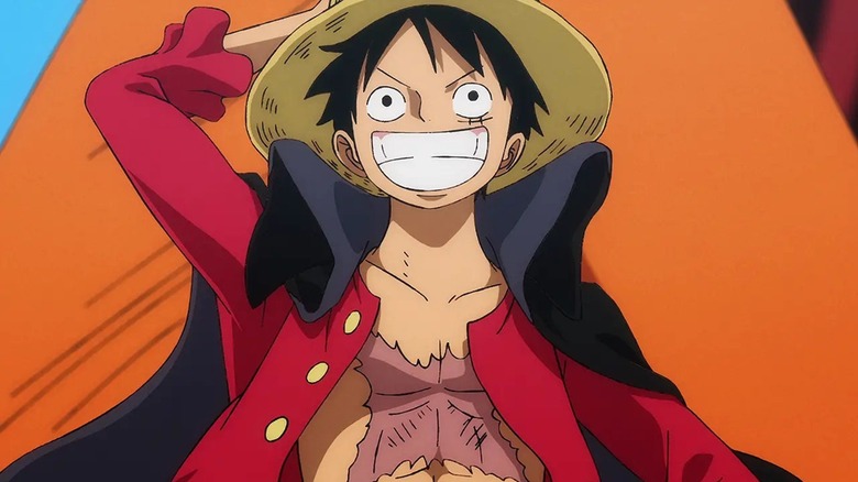 Luffy holding his straw hat on the bow of the Thousand Sunny in One Piece