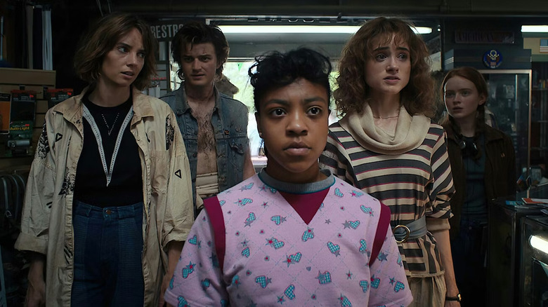Robin, Steve, Erica, Nancy, and Max standing in a garage in Stranger Things season 4