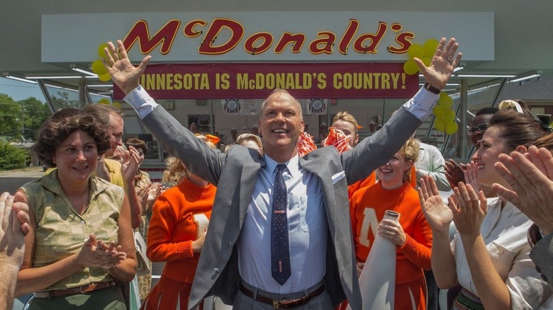 Michael Keaton as Ray Kroc with his hands up in front of McDonald's in The Founder