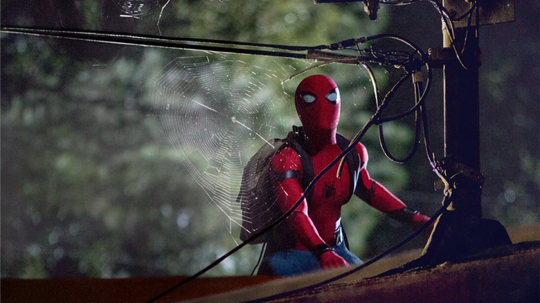 Spider-Man wearing a backpack at night looking at a spider's web in Spider-Man: Homecoming