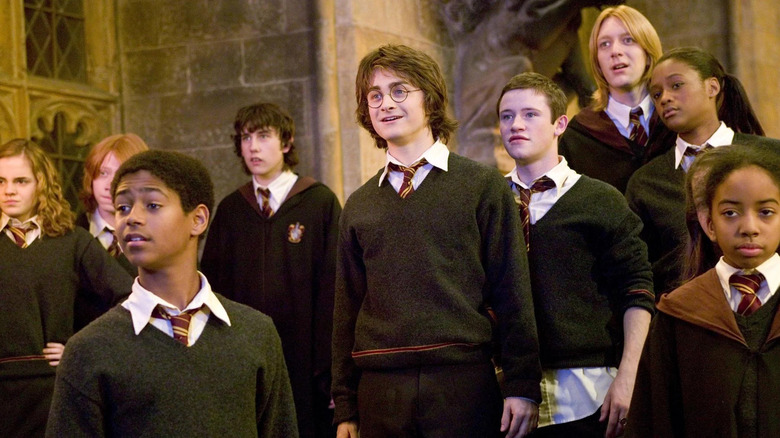 Harry surrounded by other Hogwarts students looking excited in Harry Potter and the Goblet of Fire