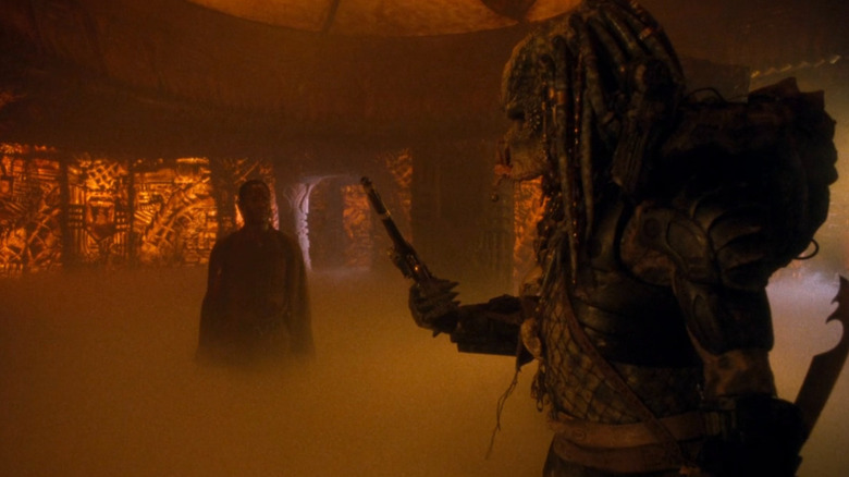 Yautja holding a gun while Mike Harrigan (Danny Glover) looks on in Predator 2