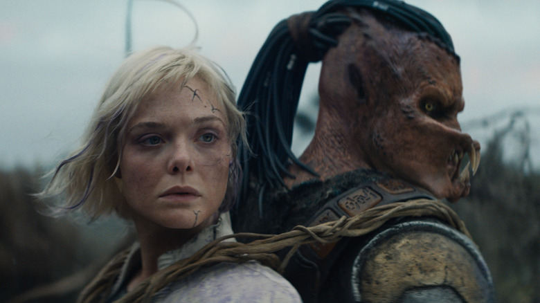 Thia (Elle Fanning) strapped to Dek's (Dimitrius Schuster-Koloamatangi) back in Predator: Badlands