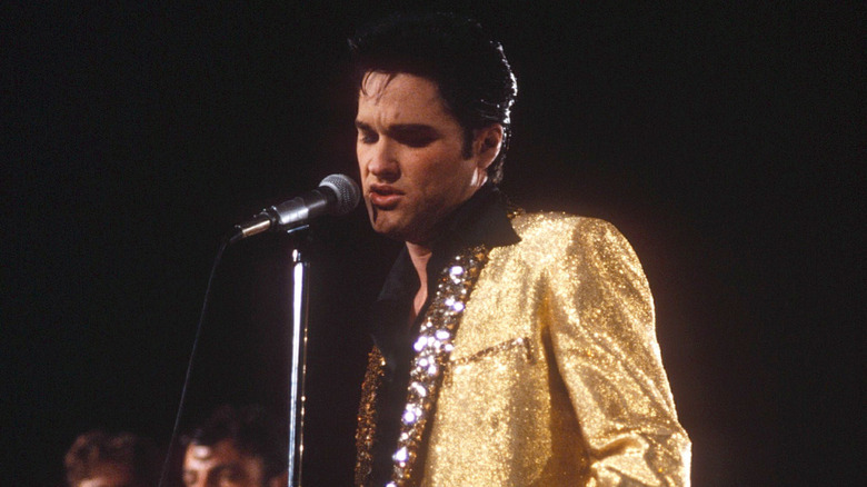 Elvis singing on stage in a shiny golden jacket in John Carpenter's Elvis