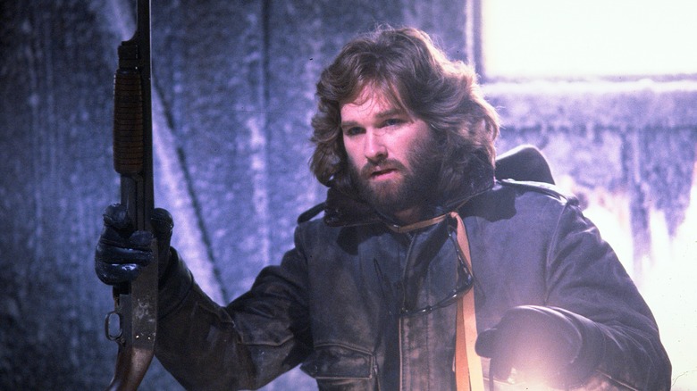 R.J. MacReady holding a shotgun and a lantern in The Thing