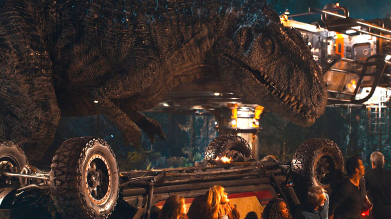 Giganotosaurus looks down on some puny humans hiding behind a truck in Jurassic World: Dominion