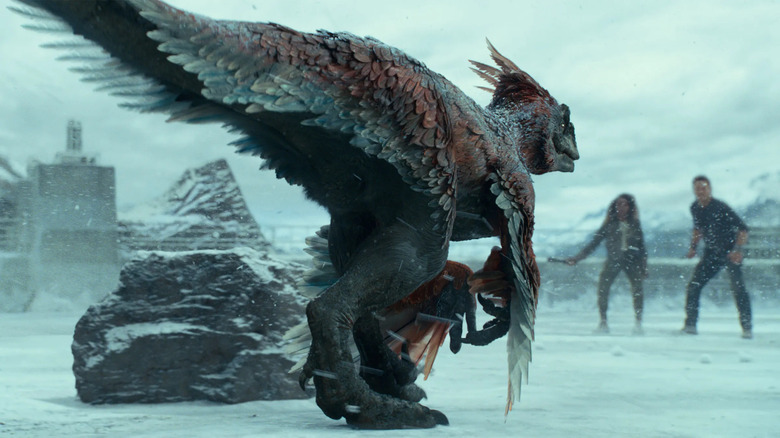 A pyroraptor approaches Owen Grady in the snow in Jurassic World: Dominion