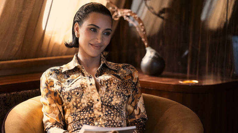 Allura with her hair slicked back smirking and sitting back in a chair in All's Fair