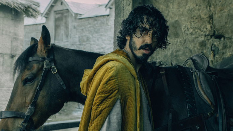 Gawain in yellow robe with horse in The Green Knight