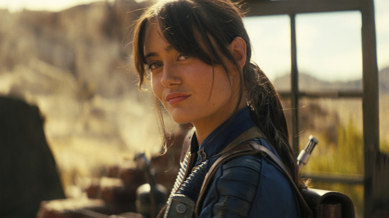 Ella Purnell as Lucy MacLean standing in a burnt-out home in Fallout