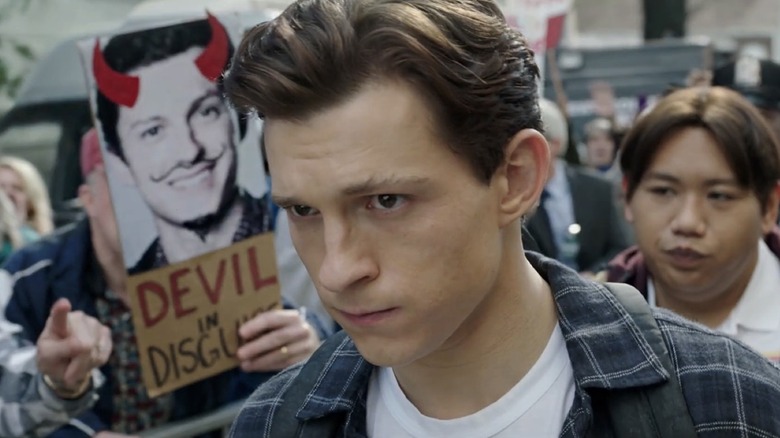 Tom Holland as Peter Parker walking in front of an angry crowd in Spider-Man: No Way Home