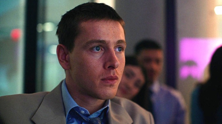 Harris Dickinson as Samuel wearing a suit and looking off screen intently in Babygirl