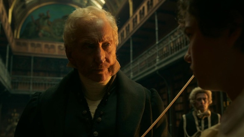 Frankenstein (2025) Charles Dance as Baron Leopold Frankenstein holding rod to punish his son Victor