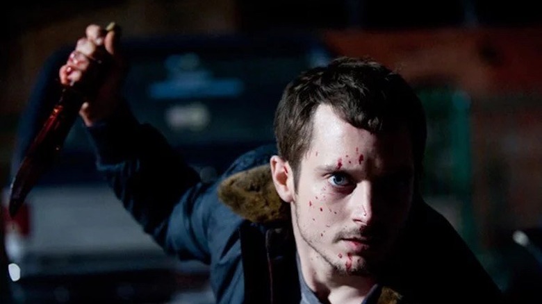 Elijah Wood holding bloody knife with blood on face in Maniac