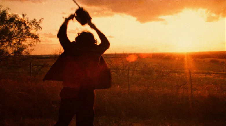 Texas Chainsaw Massacre's Leatherface holding chainsaw in sunset