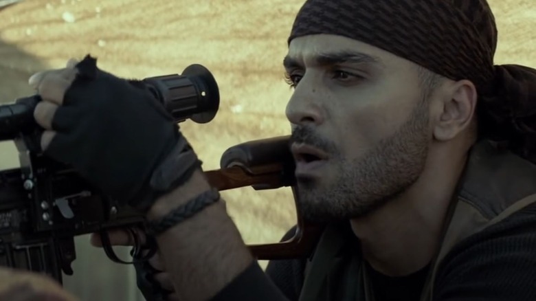 Sammy Sheik as Mustafa adjusting a rifle scope in American Sniper