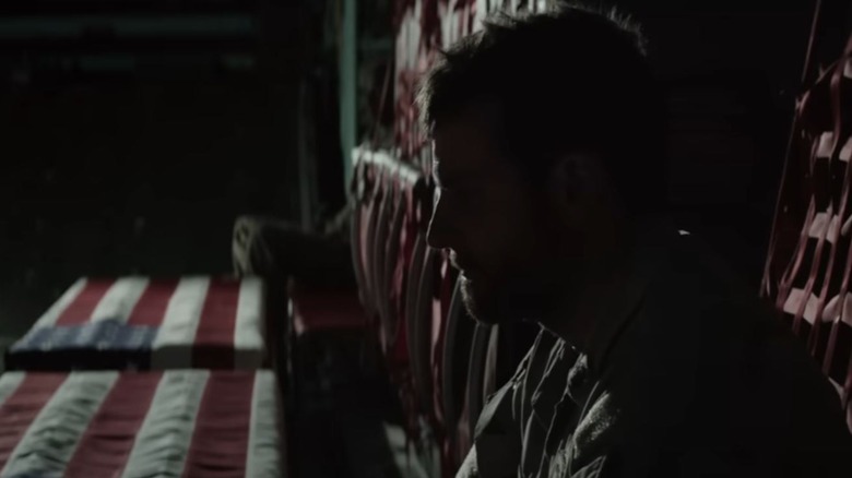 Bradley Cooper as Chris Kyle sitting in a cargo plane with coffins in American Sniper