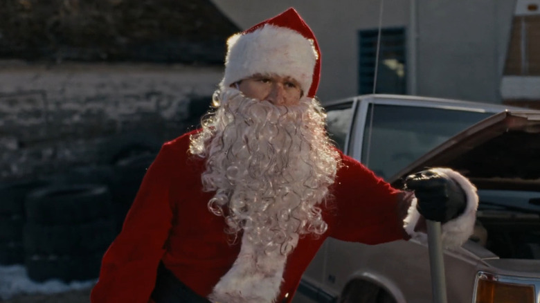Rohan Campbell as Billy in his Santa costume leaning on a car jack in Silent Night, Deadly Night (2025)