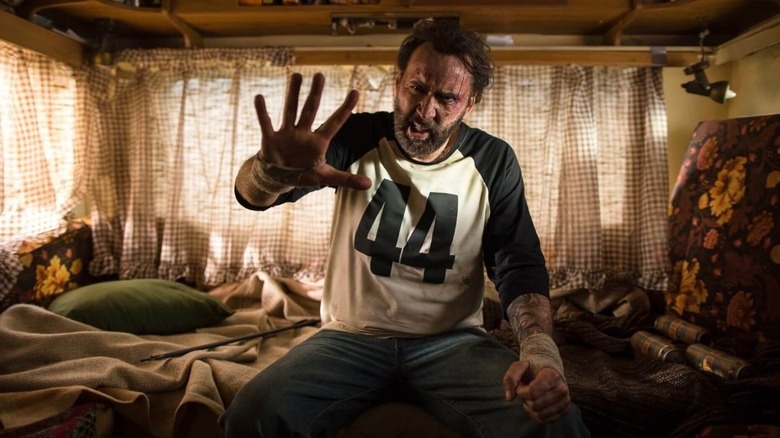 Nicolas Cage as Red Miller raising his right hand in front of him in Mandy