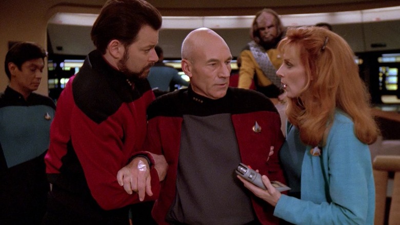 Riker and Dr. Crusher holding up Captain Picard in Star Trek: The Next Generation