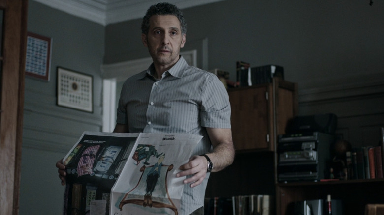 John Stone de John Turturro se tient dans son appartement tenant un journal dans The Night Of