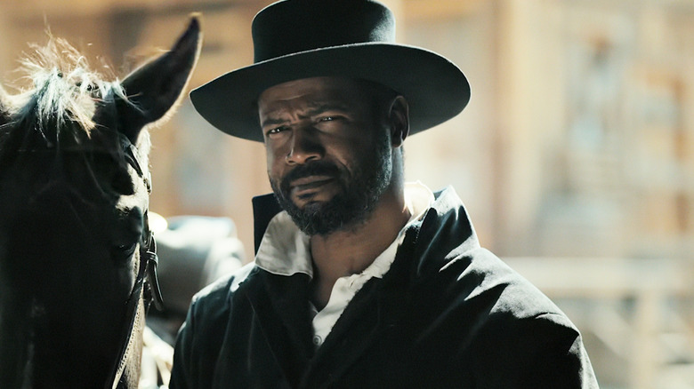 Isaiah Mustafa's Cicero squints as he stands in front of a horse in Muder at Yellowstone City