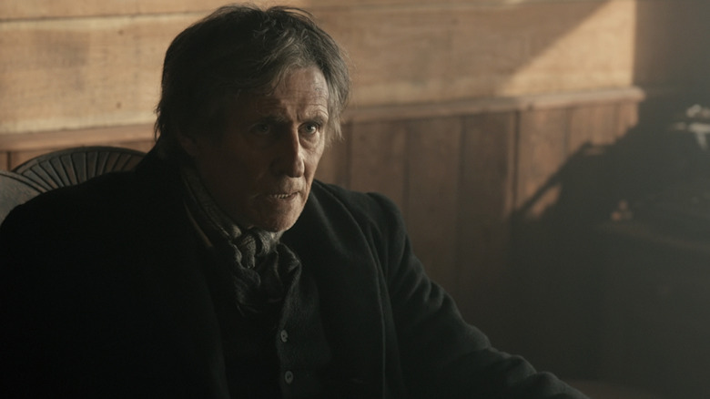 Gabriel Byrne's Sheriff Jim Ambrose looks up as he sits in a chair in Muder in Yellowstone City
