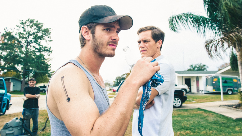 Andrew Garfield as Dennis and Michael Shannon as Rick standing in the front yard of a reposessed home in 99 Homes