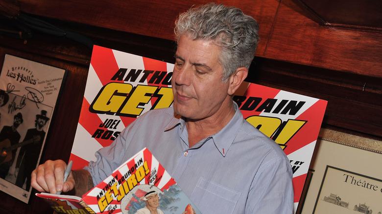 Anthony Bourdain holding and signing a copy of his comic Get Jiro!