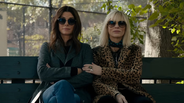 Sandra Bullock as Debbie and Cate Blanchett as Lou sitting on a bench in Ocean's 8