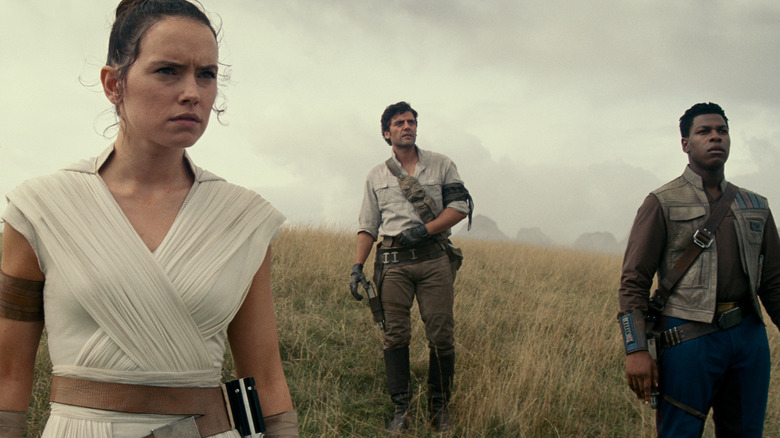 Rey (Daisy Ridley), Poe Dameron (Oscar Isaac), and Finn (John Boyega) standing together, witnessing the damage of the second Death Star in "Star Wars: The Rise of Skywalker"