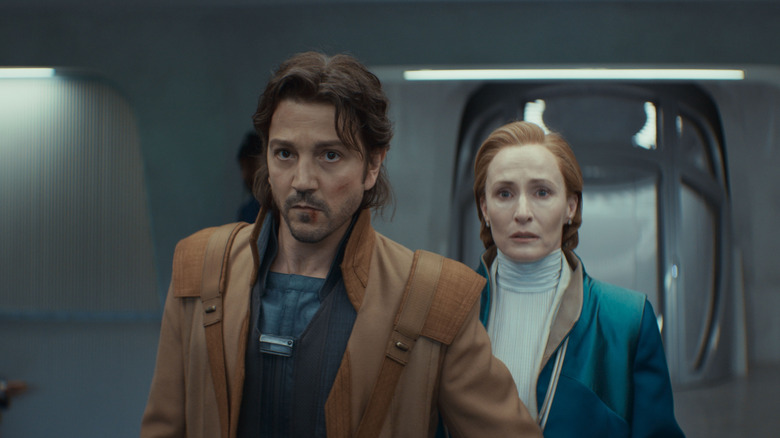 Diego Luna as Cassian Andor standing in front of Genevieve O'Reilly as Mon Mothma in Andor