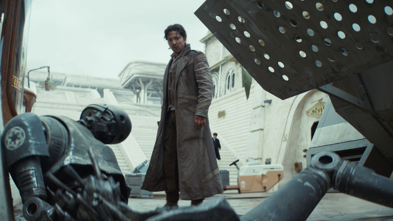Diego Luna as Cassian Andor standing over a mangled K-2SO (Alan Tudyk) in Andor
