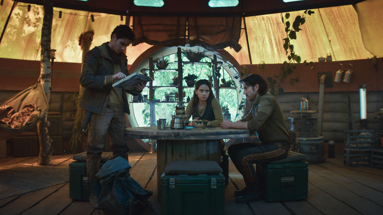 Muhannad Bhaier as Wilmon Paak, Adria Arjona as Bix Caleen, and Diego Luna as Cassian Andor gathered around a table in Andor season 2