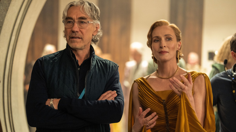 Showrunner Tony Gilroy standing with his arms crossed next to Genevieve O'Reilly as Mon Mothma on the set of Andor season 2