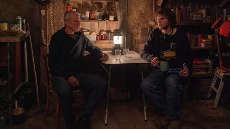A behind-the-scenes picture of Daniel Day-Lewis seated at a table with director Ronan Day-Lewis on the set of Anemone