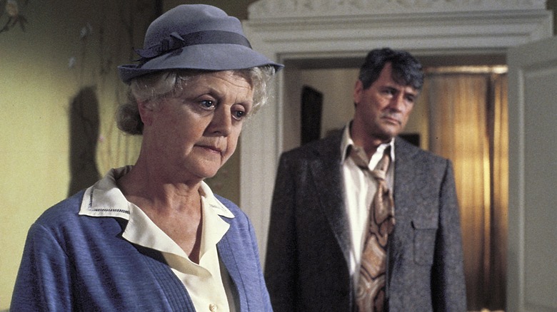 Miss Marple standing next to Jason Rudd in the cracked mirror.
