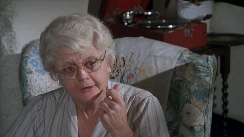 Miss Marple in glasses, sitting, in the cracked mirror