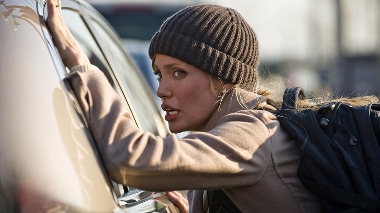 Evelyn Salt wearing a beanie and catching her breath while leaning against a vehicle in Salt