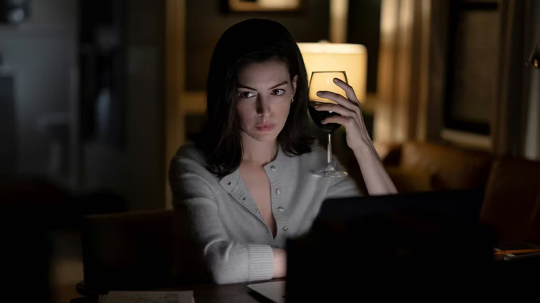 Verity holding a glass of wine and writing in Verity