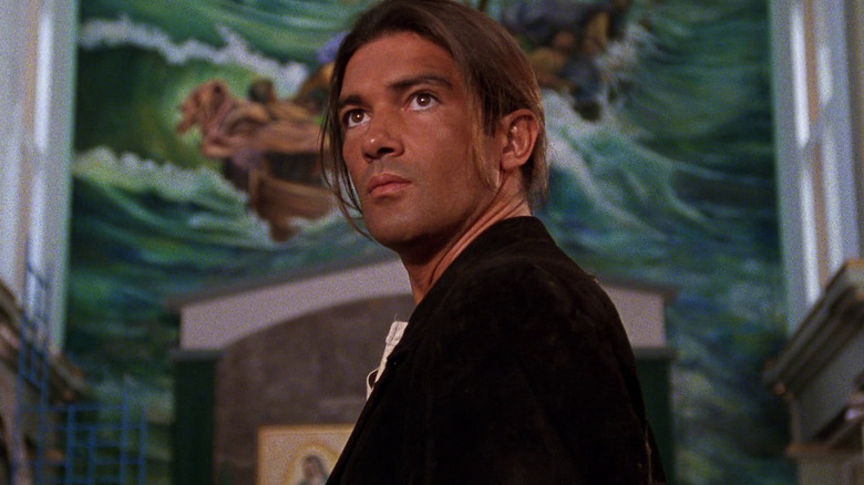 El Mariachi looking over his shoulder in front of a mural in Desperado
