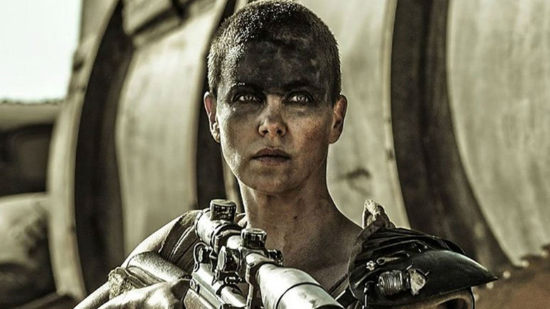 woman with short hair covered in grease holding a gun