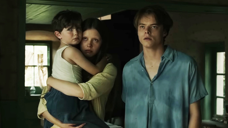 Charlie Heaton's William Marrowbone stands alongside Mia Goth's Jane Marrowbone as she holds Matthew Stagg's Samuel Marrowbone in Marrowbone